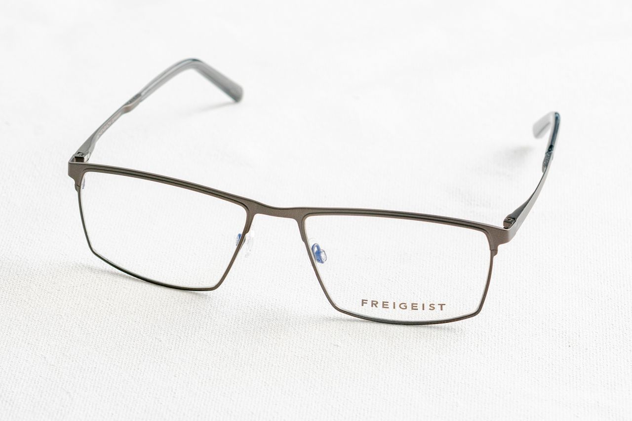Close-up of stylish Freigeist eyeglasses on white surface, minimalist style.