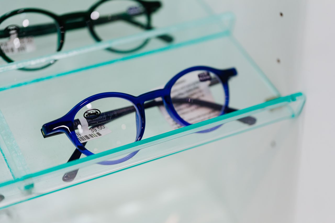 Modern blue eyeglasses showcased in a glass display case, perfect for fashion and optics themes.
