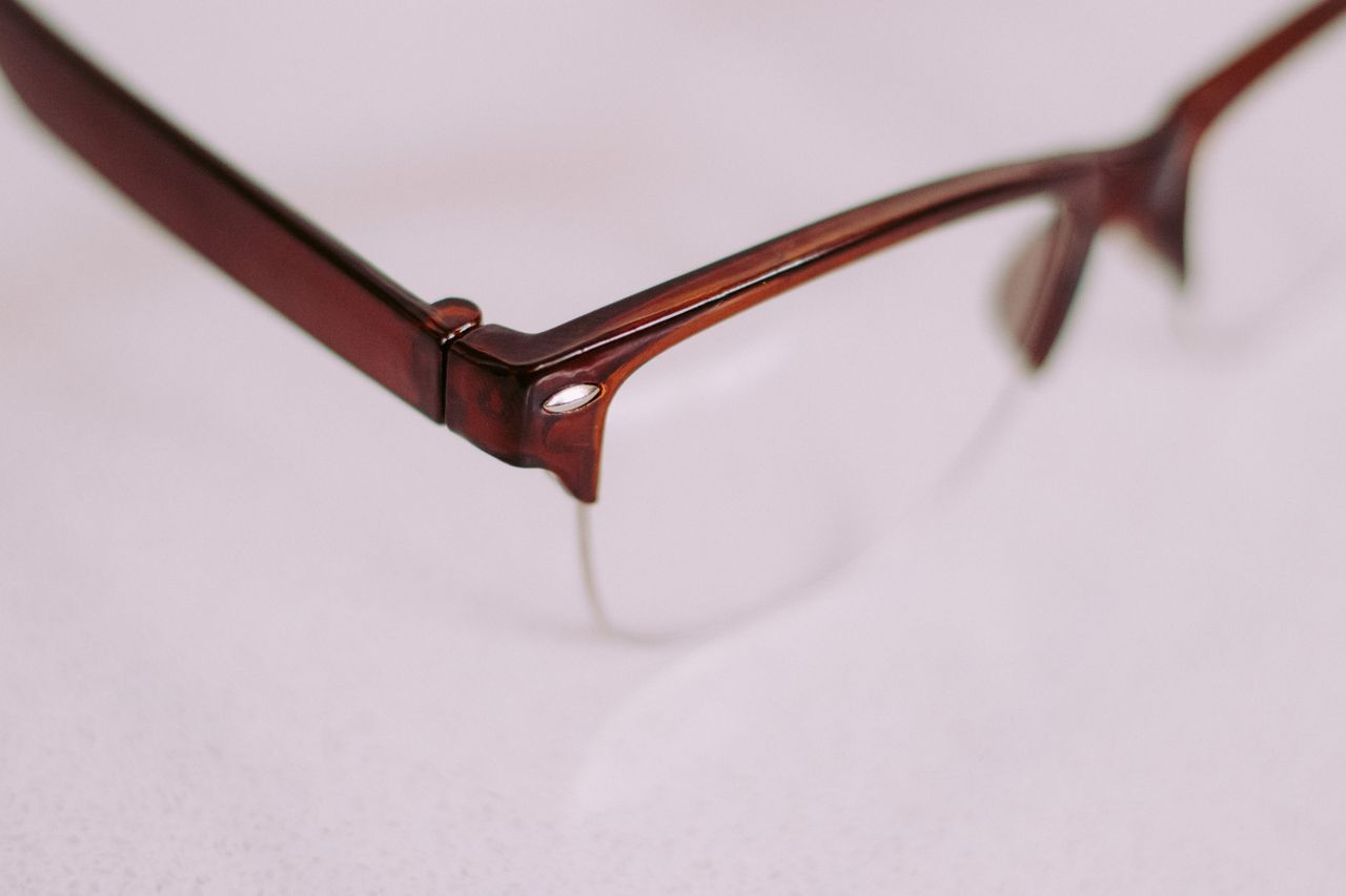 A detailed artistic close-up of a brown vintage style eyeglasses frame with a focus on the corner.